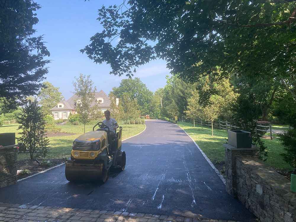 Asphalt driveway rolling with compactor during residential paving project services in Cranston, RI